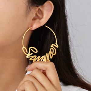 Close-up of a woman wearing a large gold Custom Name Hoop Earring with a personalized cursive name design