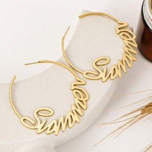 Gold Custom Name Hoop Earrings with a personalized cursive name design displayed on a neutral stone surface