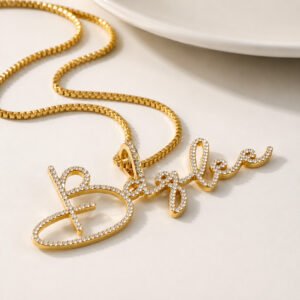 Personalized gold script crystal name necklace with cubic zirconia on a white minimalist background